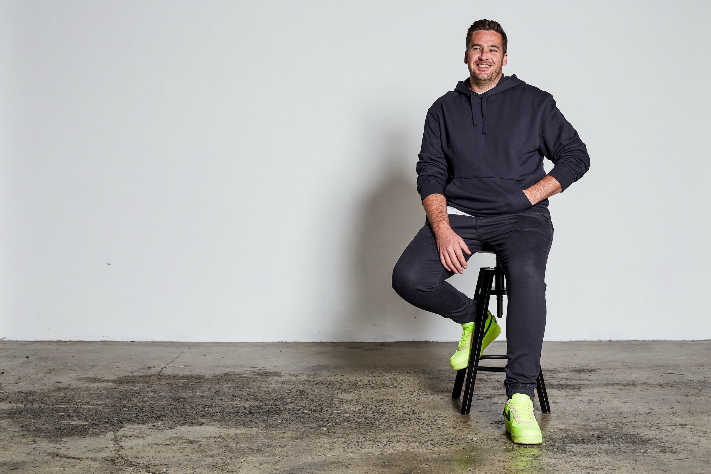 AI keynote speaker Gavin Reddrop seated on a stool in a studio, smiling